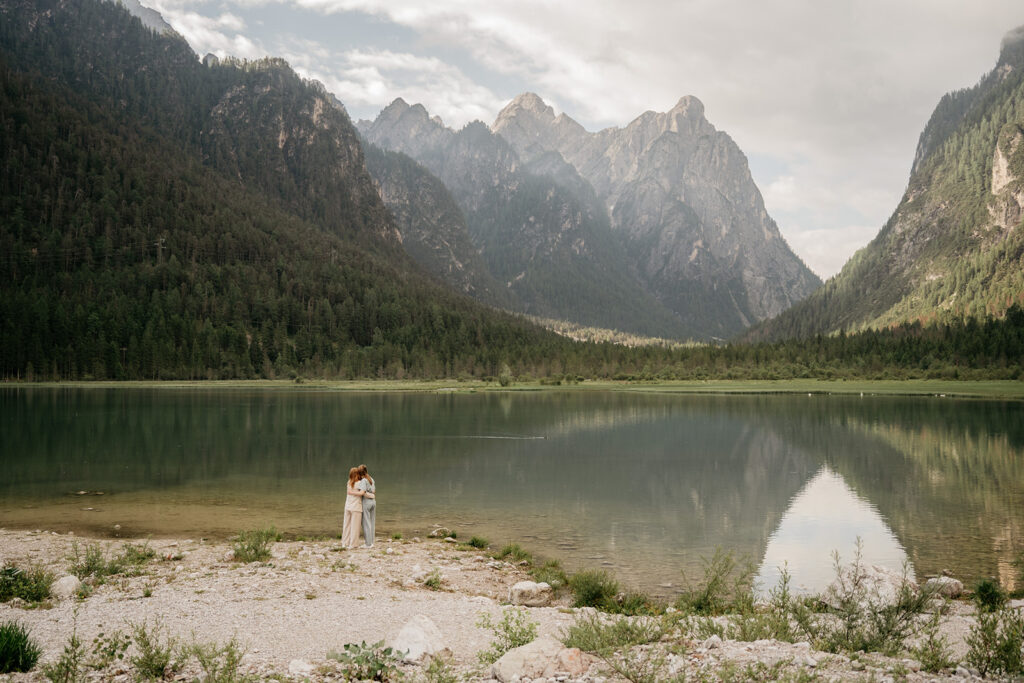 Couple embraces by tranquil mountain lake.