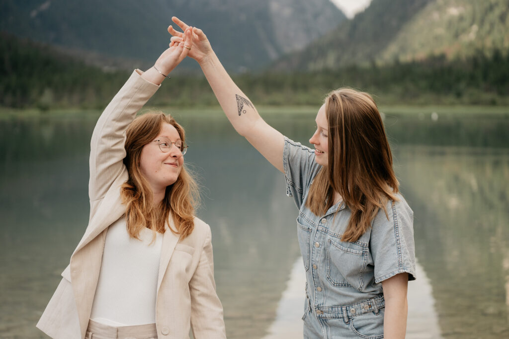 Two friends holding hands by a lake.