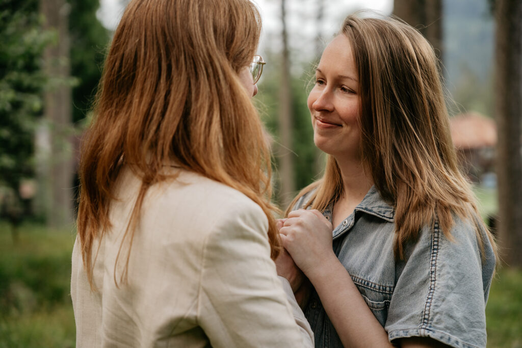 Two people holding hands outdoors, smiling.