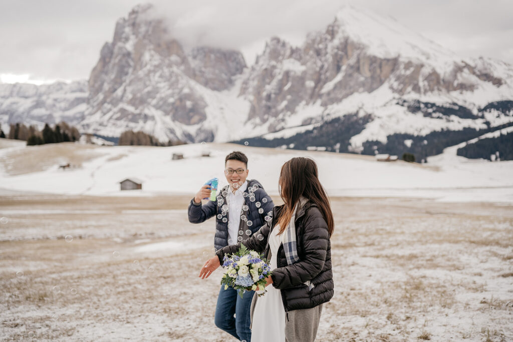 Couple playing with bubbles in snowy mountains.