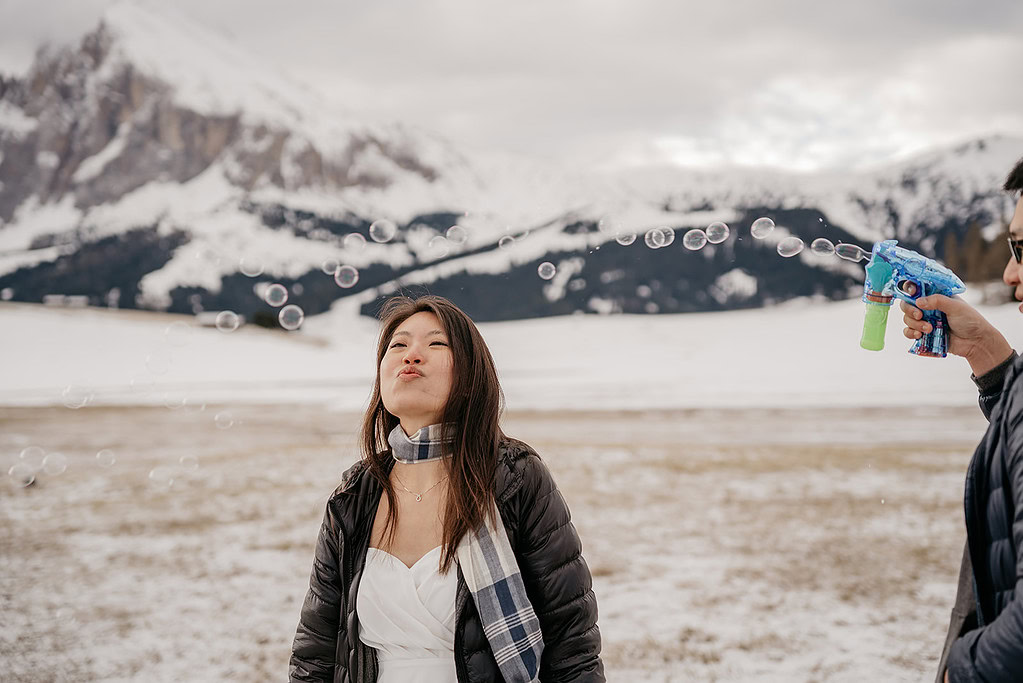 Woman enjoying bubbles in snowy mountain landscape.