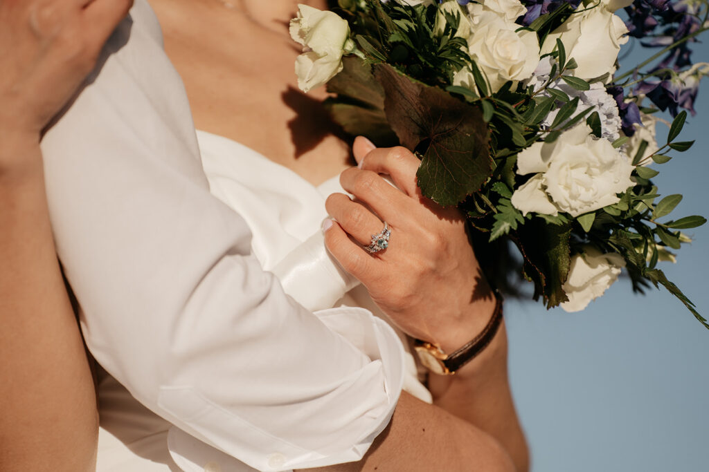 Bride holding wedding bouquet with ring visible.