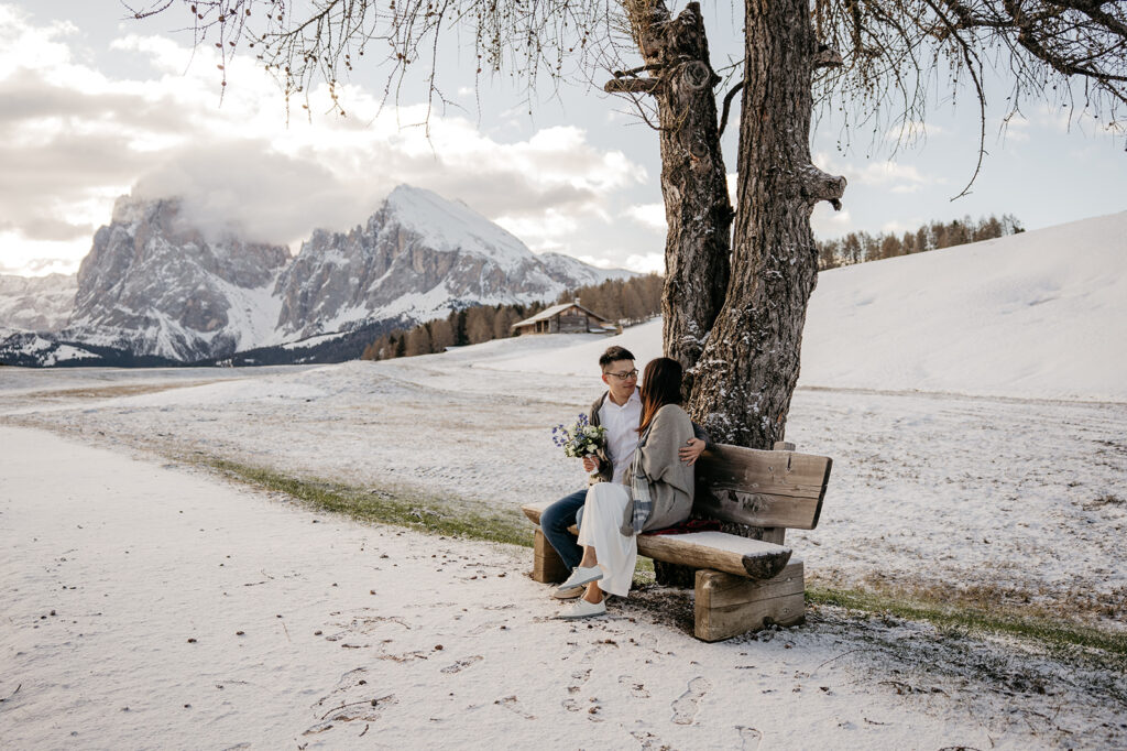 Couple sitting on bench in snowy mountain landscape