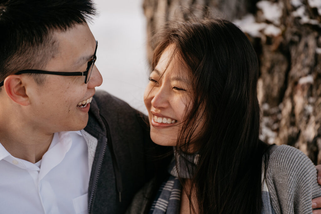 Smiling couple outdoors near trees.