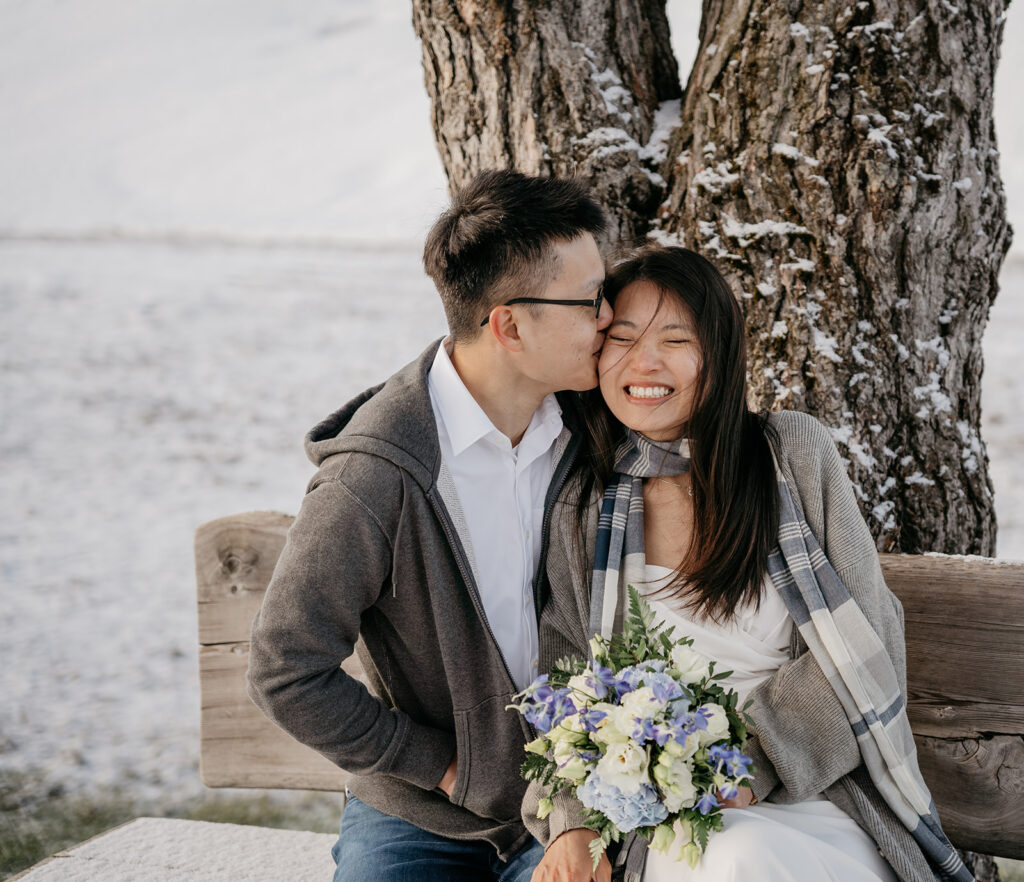 Happy couple embraces in snowy landscape.