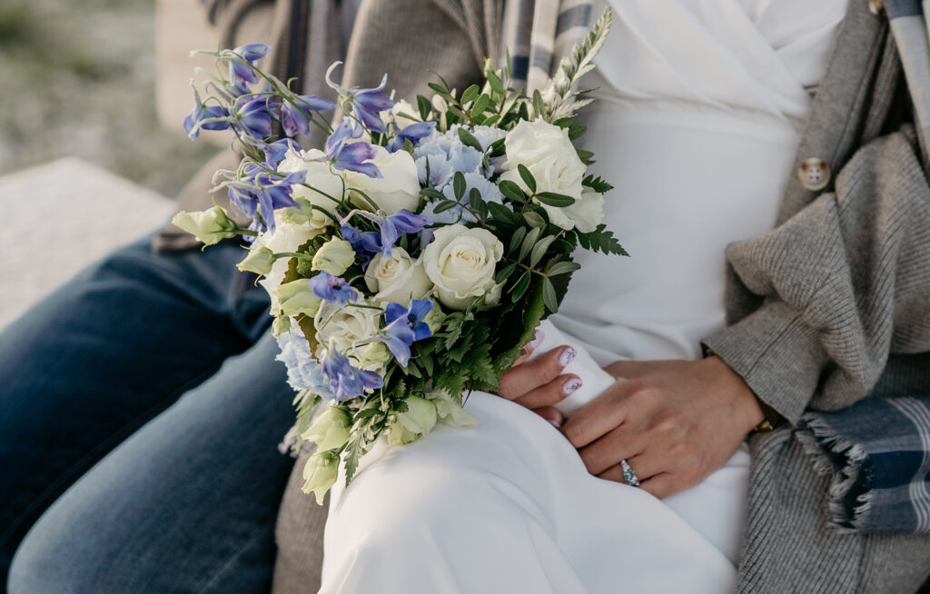 Bride holding bouquet of blue and white flowers.