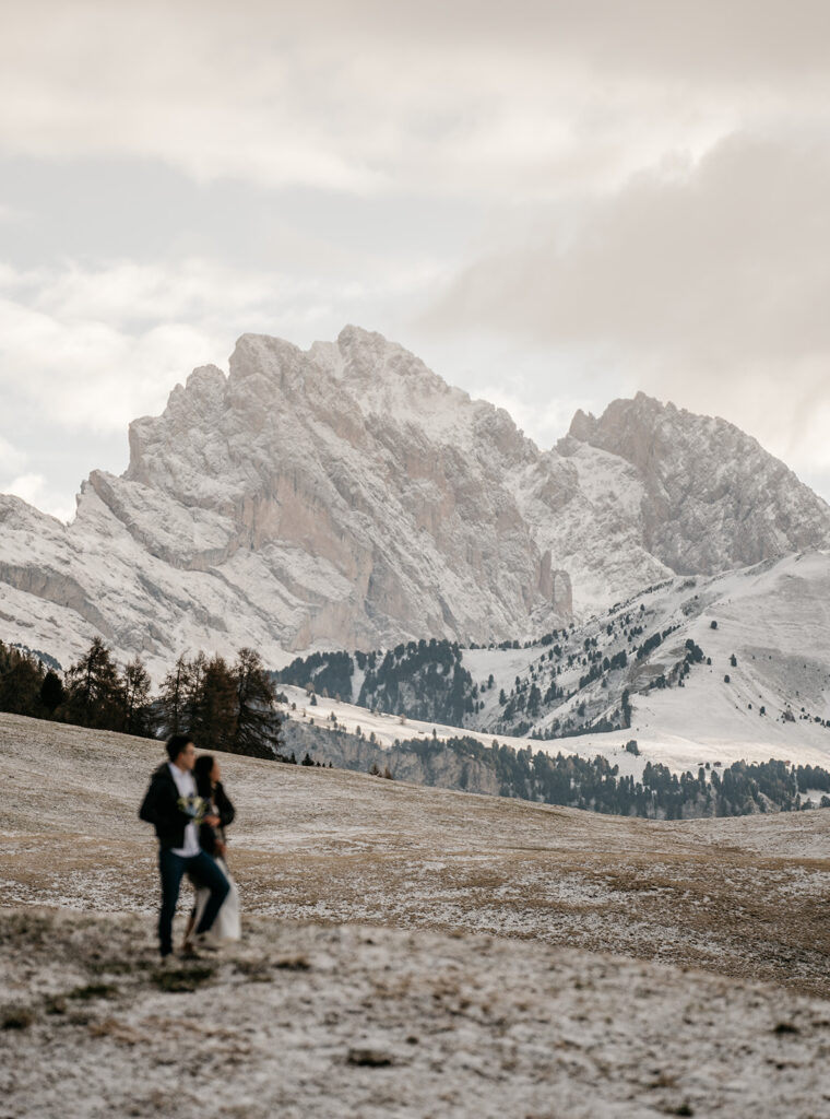 Couple in front of snowy mountain landscape.