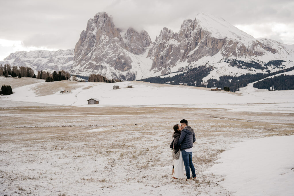 Couple embracing in snowy mountain landscape.