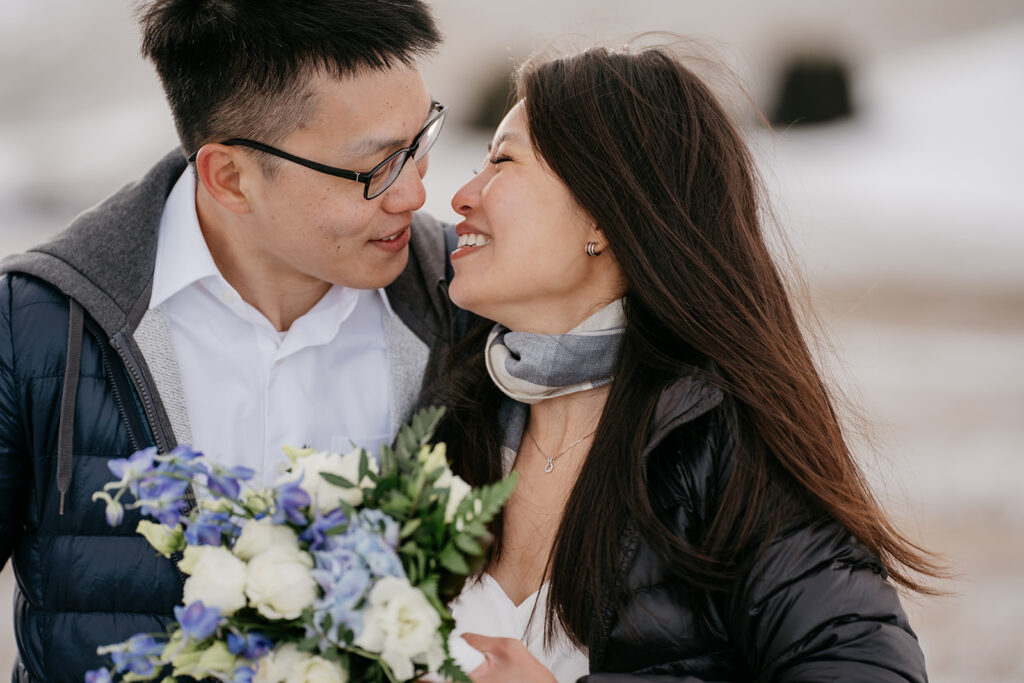 Couple smiling with bouquet outdoors in winter