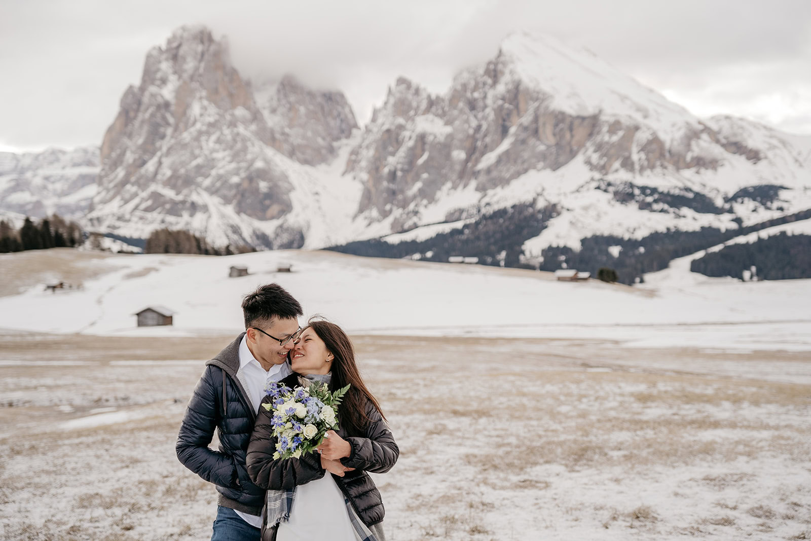 Couple embracing in snowy mountain landscape.