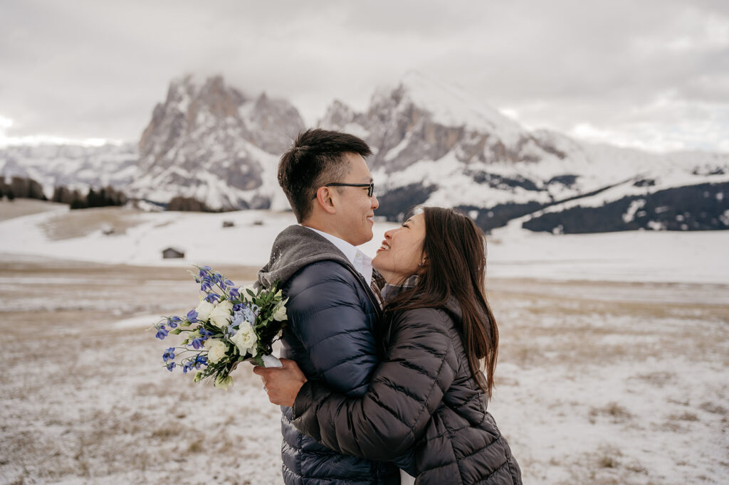 Couple embraces with mountain view in the background.