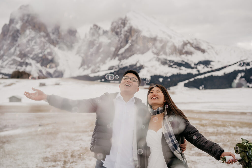 Couple enjoying snowy mountain landscape with bubbles.