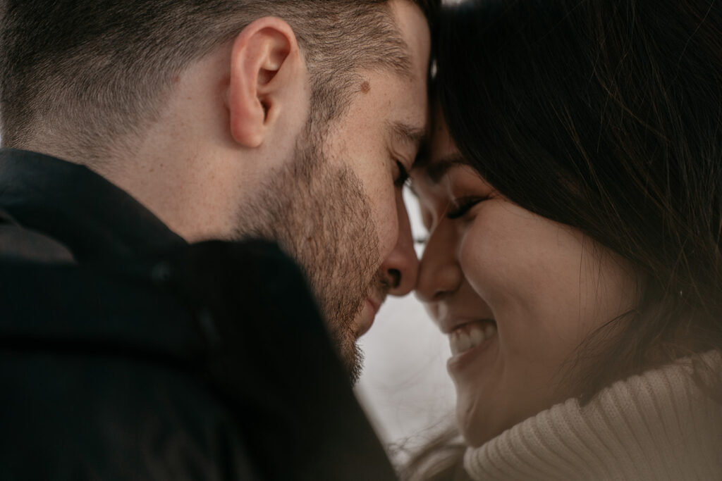 Close-up of couple smiling and touching foreheads.