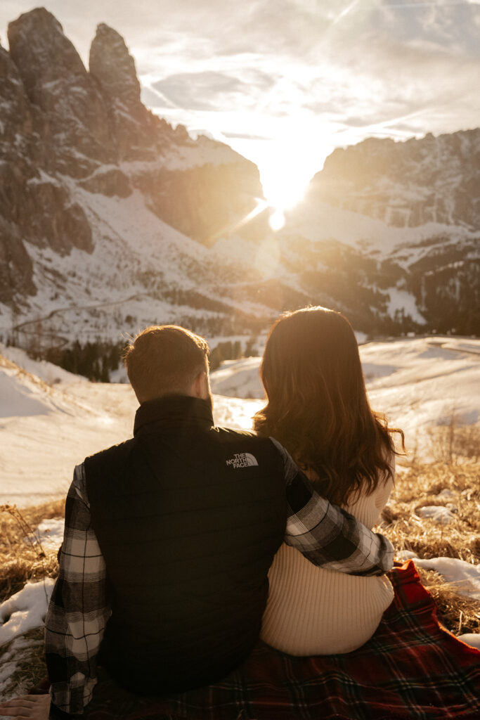 Couple enjoying snowy mountain sunset view.