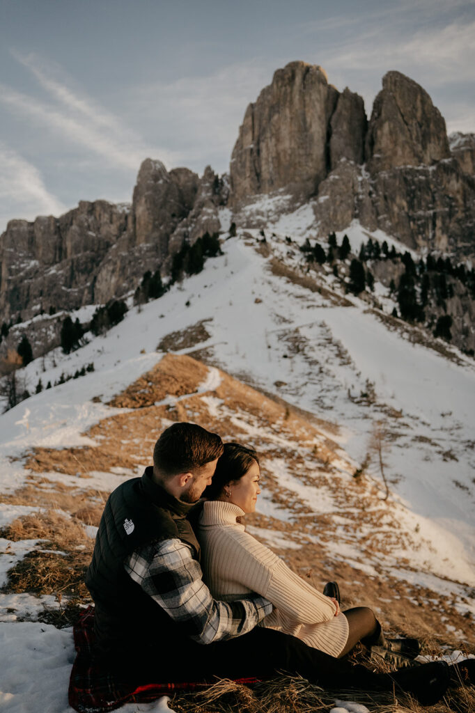 Couple sitting on snowy mountain enjoying view