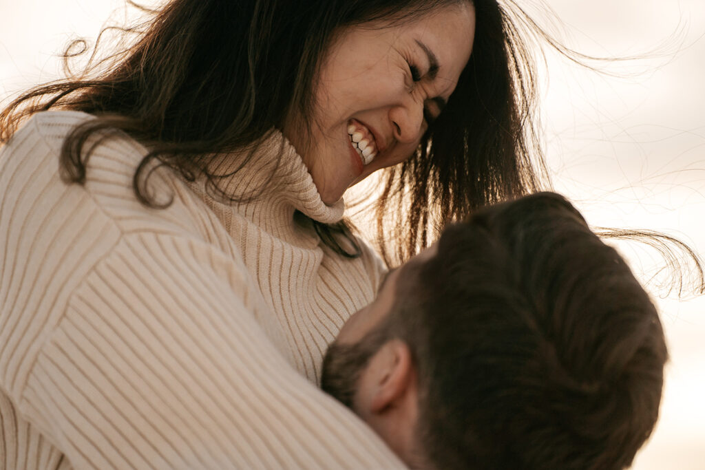 Smiling woman embraces partner, warm sunset background.