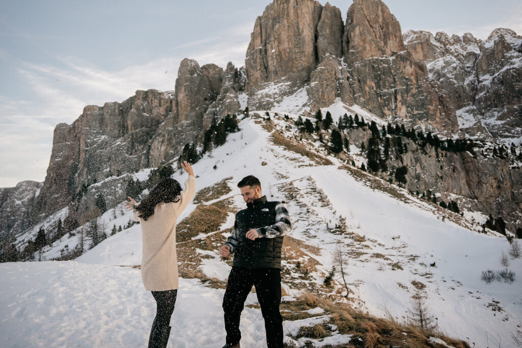 Couple playing in snowy mountain landscape.