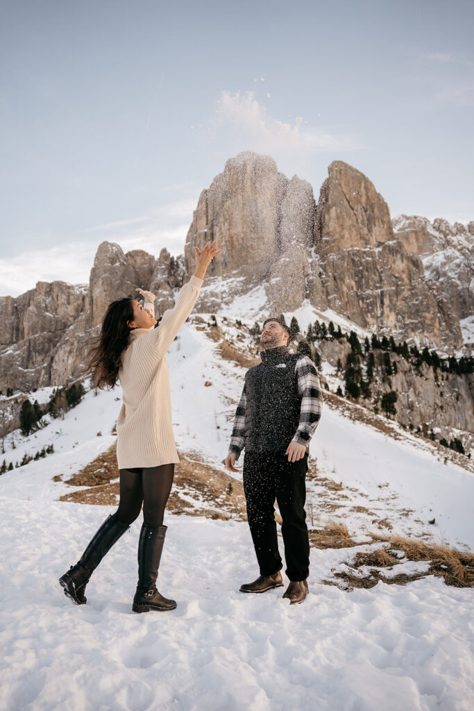 Couple playing in snowy mountain landscape.