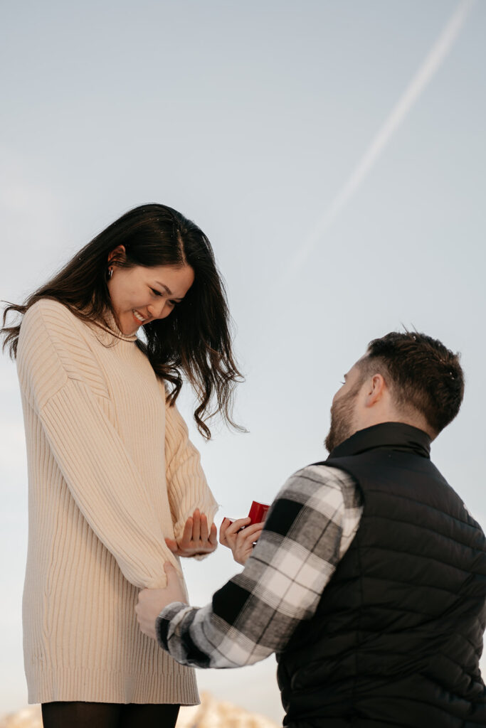 Man proposing outdoors, holding ring box