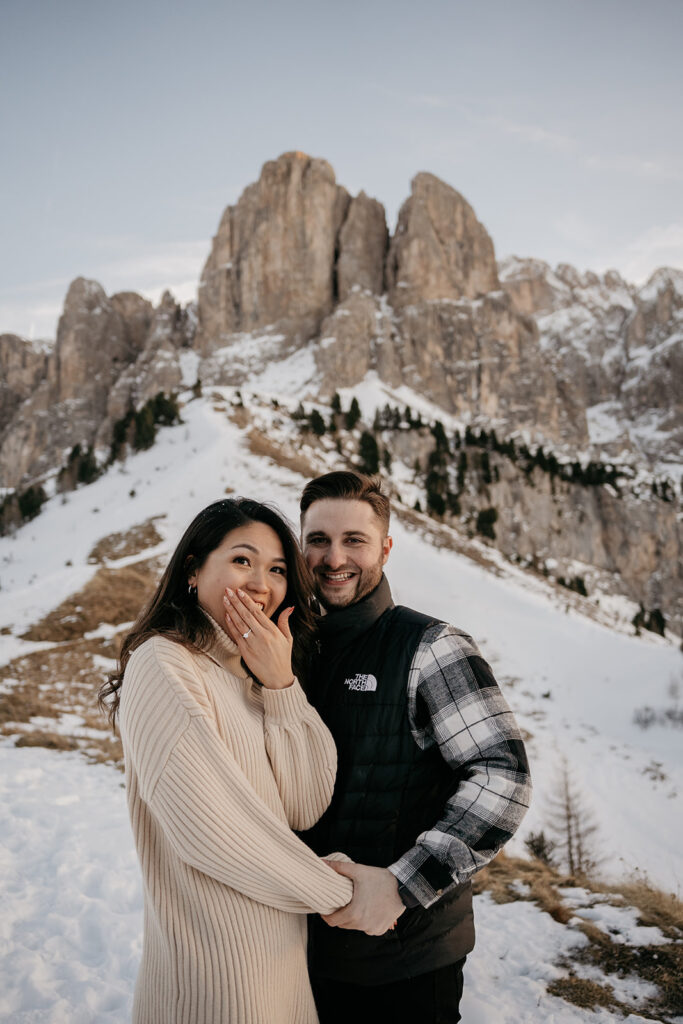 Couple celebrating engagement in snowy mountains.