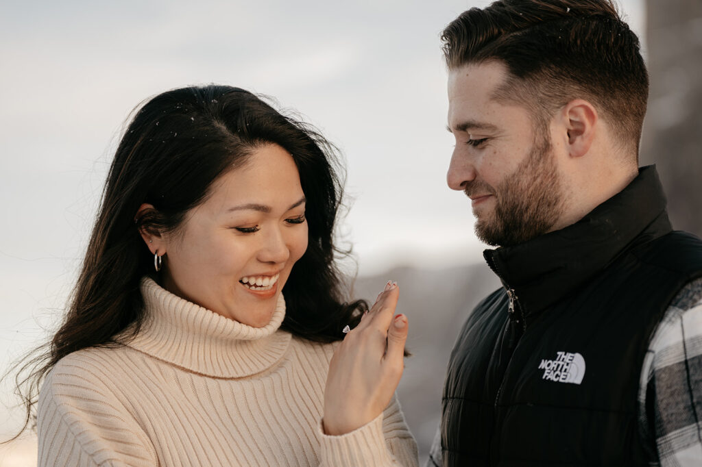 Couple smiling, woman showing engagement ring.