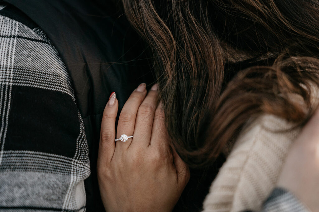 Close-up of hand with engagement ring on shoulder.