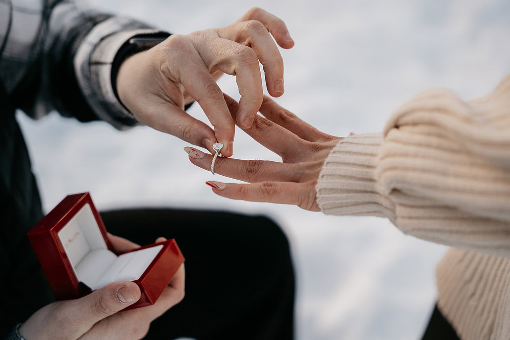 Person proposing with diamond engagement ring