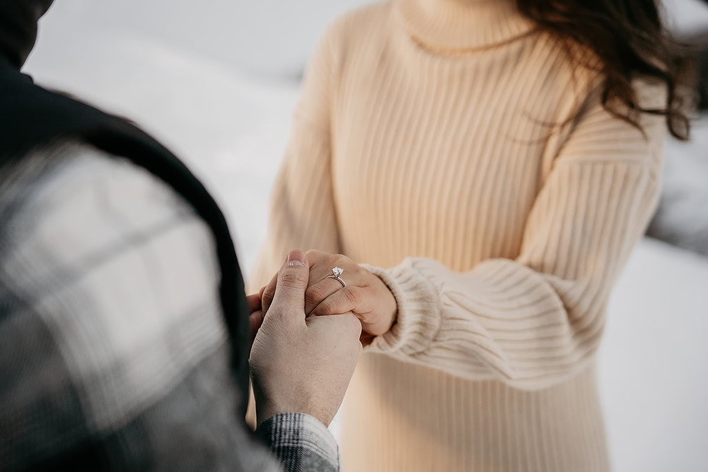 Couple holding hands with engagement ring