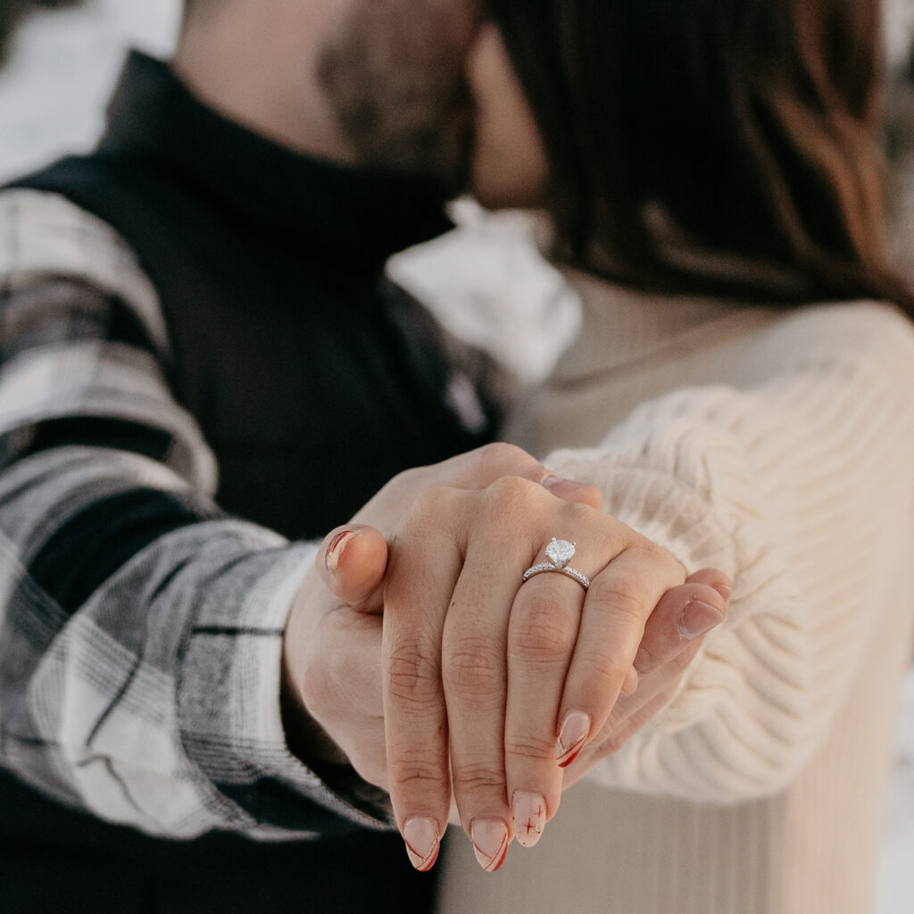 Couple holding hands, engagement ring visible.