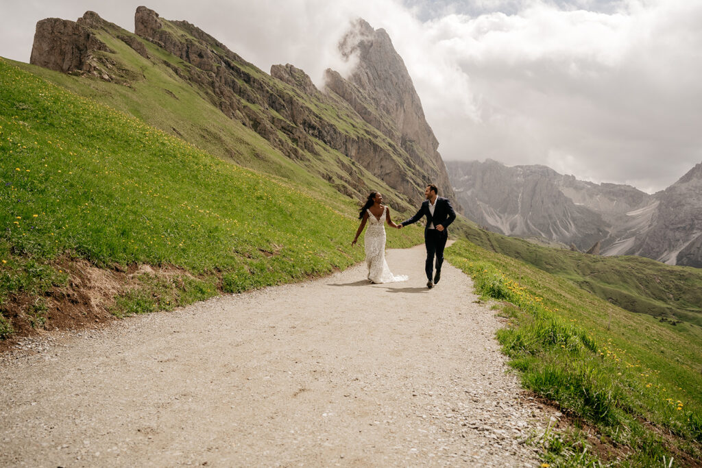 Wedding couple running in mountain landscape.