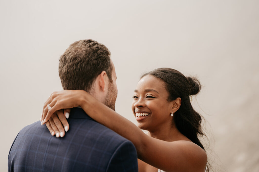 Smiling couple embracing, showing engagement ring