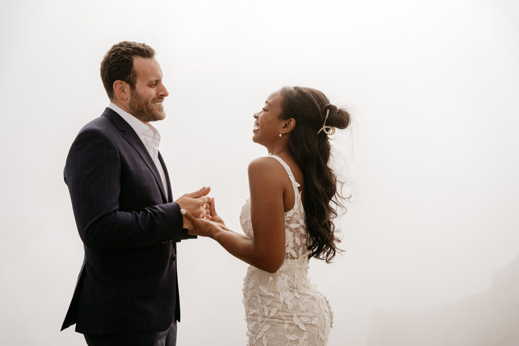 Bride and groom holding hands, smiling joyfully.