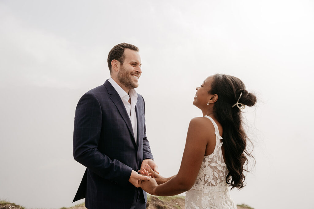 Couple holding hands, smiling at each other.