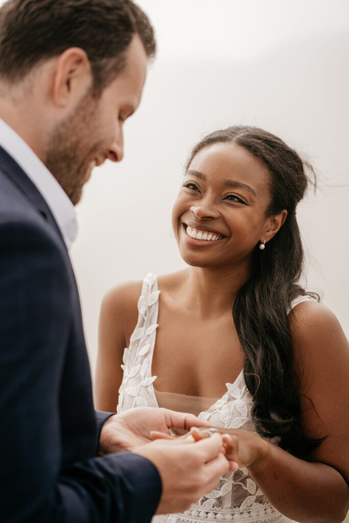 Couple smiling and exchanging rings.