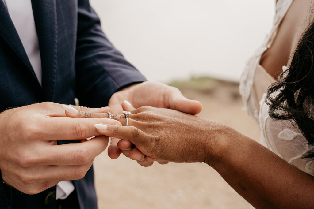 Wedding couple exchanging rings outdoors