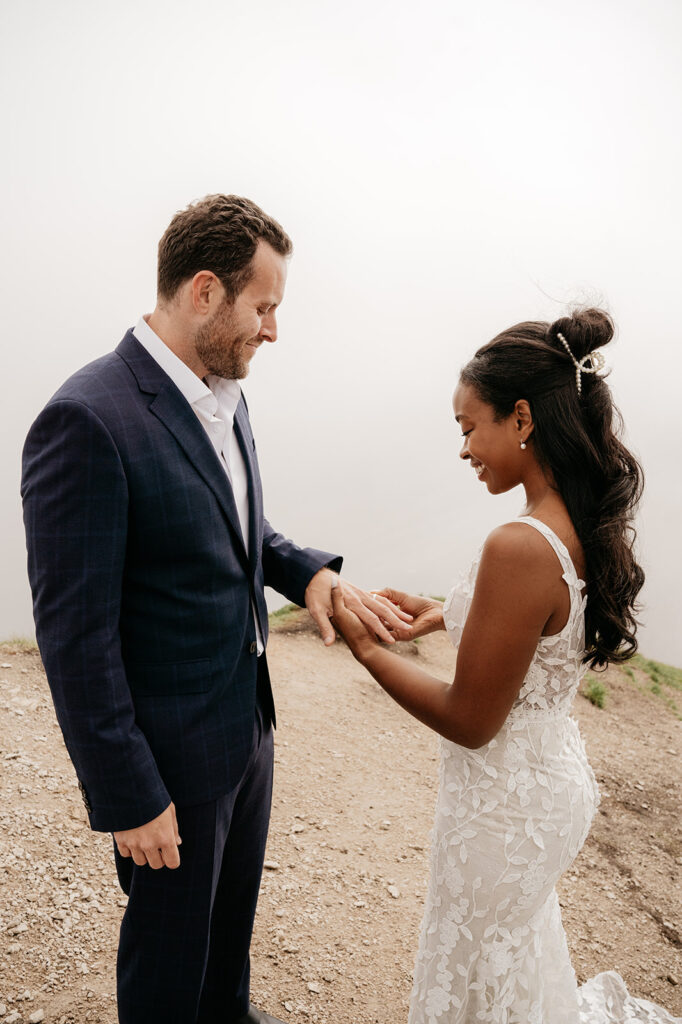 Couple exchanging rings during outdoor wedding ceremony.