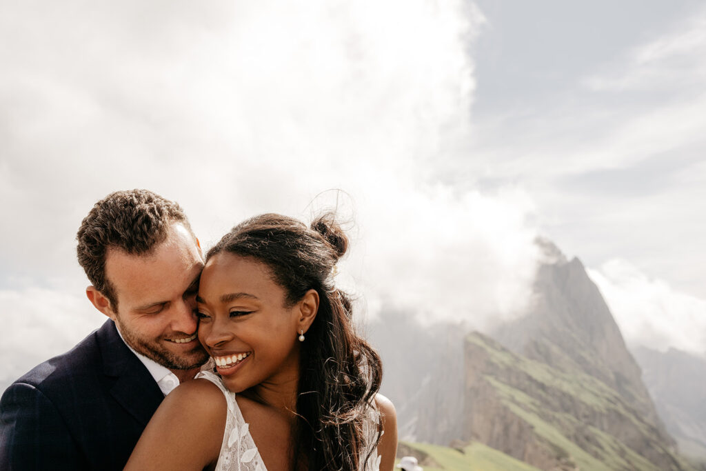 Couple smiling with mountain backdrop.