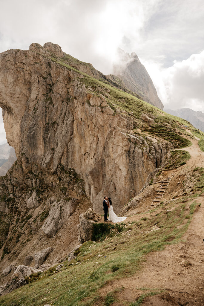 Couple embracing on mountain terrain, dramatic backdrop