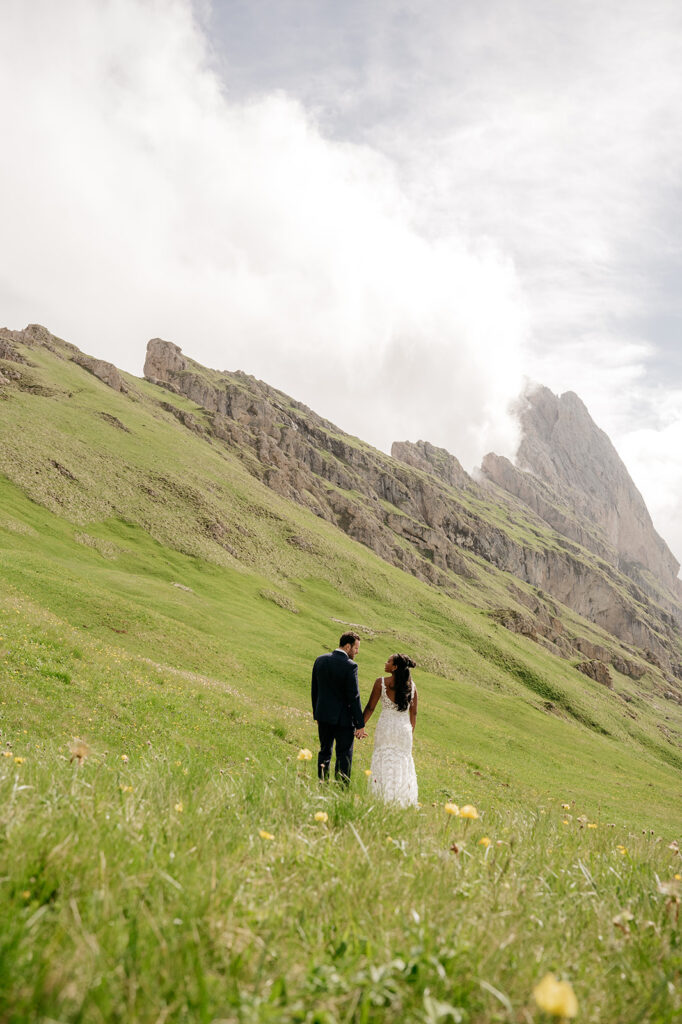 Couple holding hands on a scenic mountain meadow.