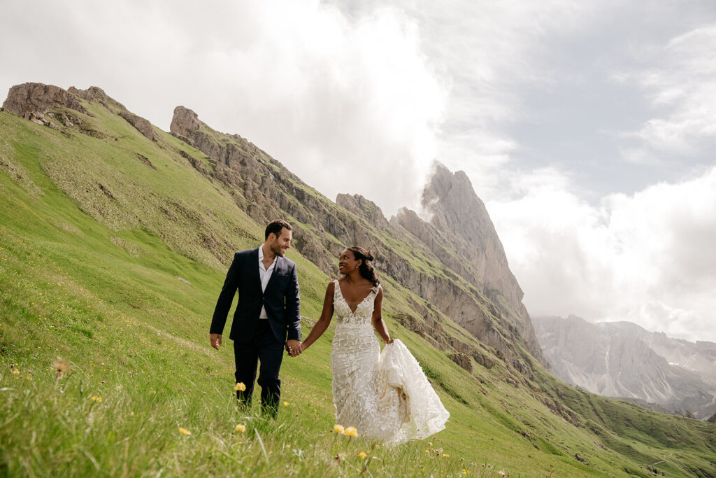 Bride and groom walking in mountain meadow