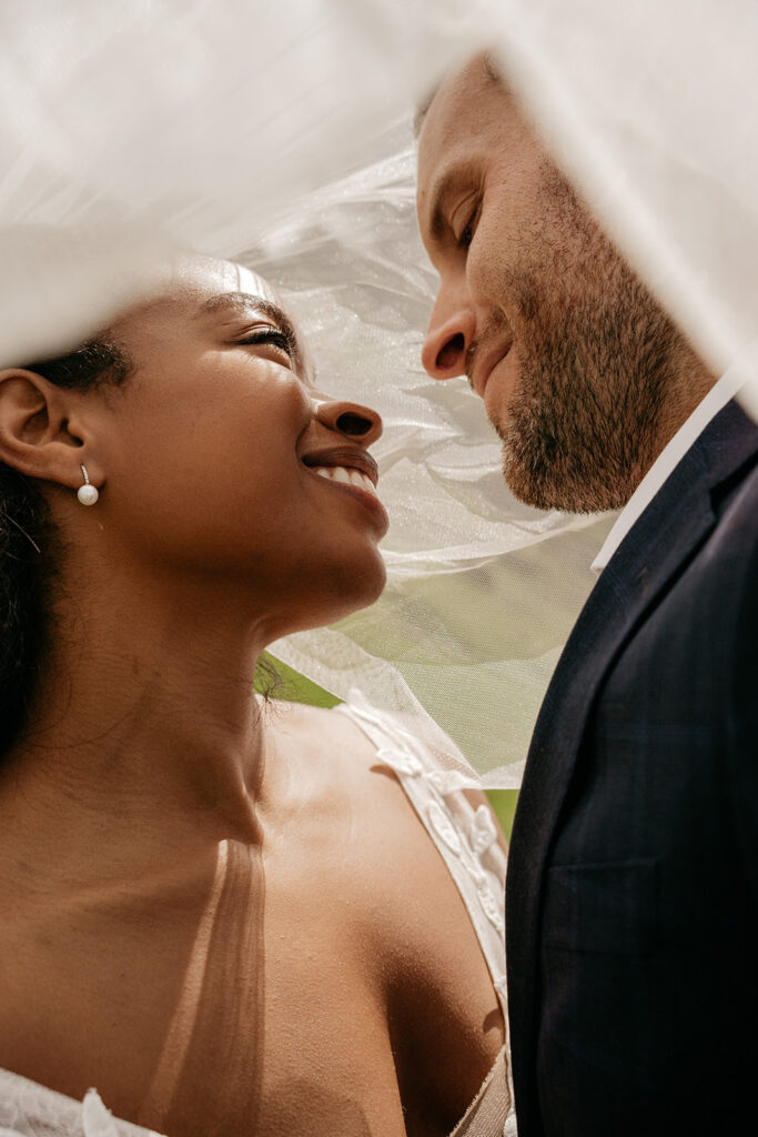 Bride and groom smiling under veil