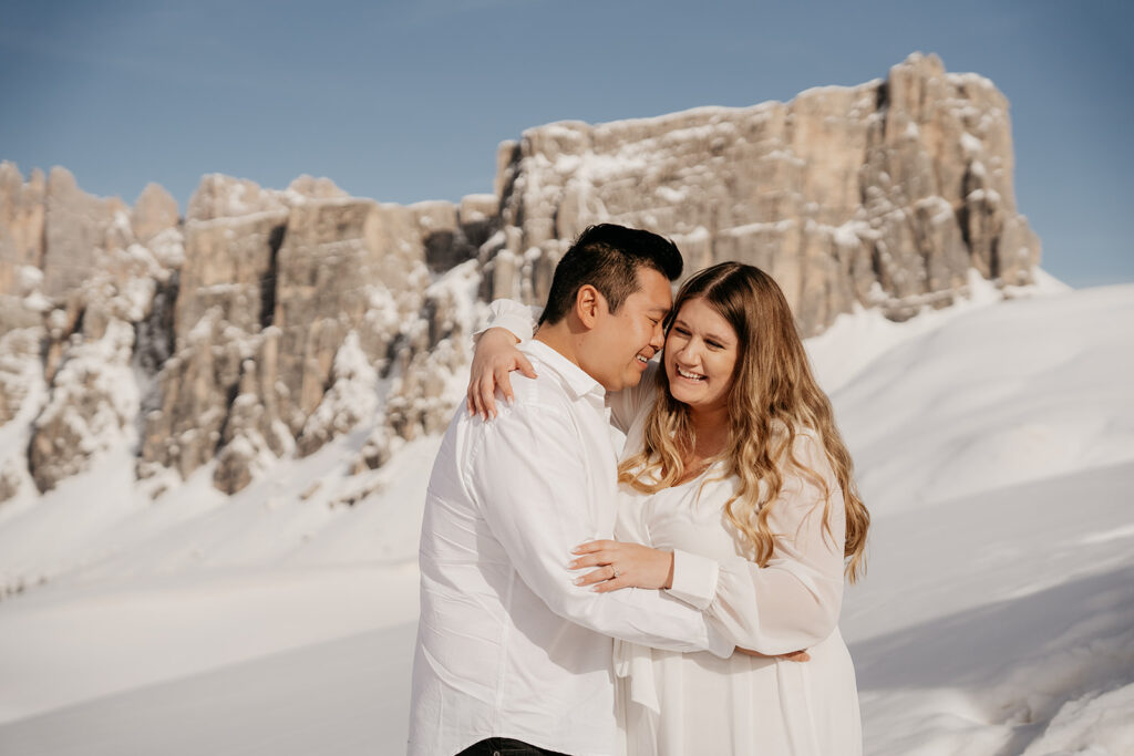 Couple embracing in snowy mountain landscape.