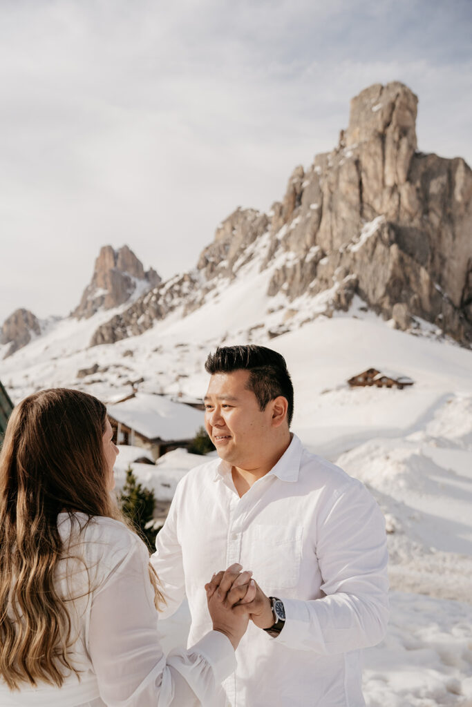 Couple holding hands in snowy mountain landscape.