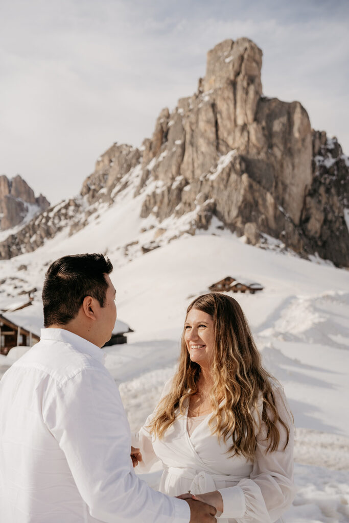 Couple smiling in snowy mountain landscape.