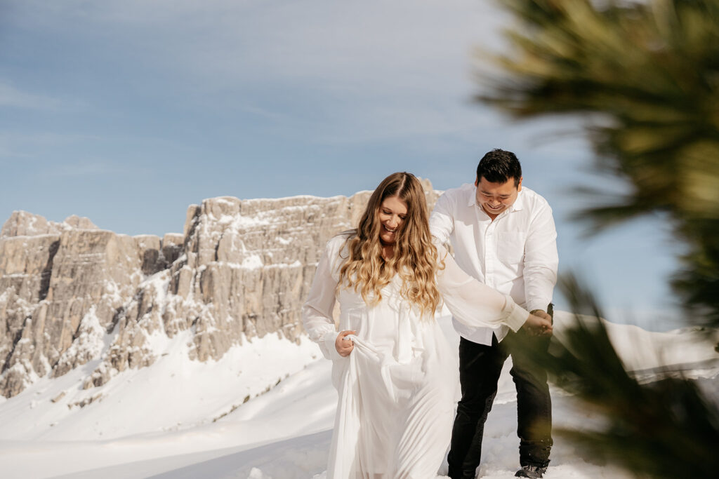 Couple laughing in snowy mountain landscape.