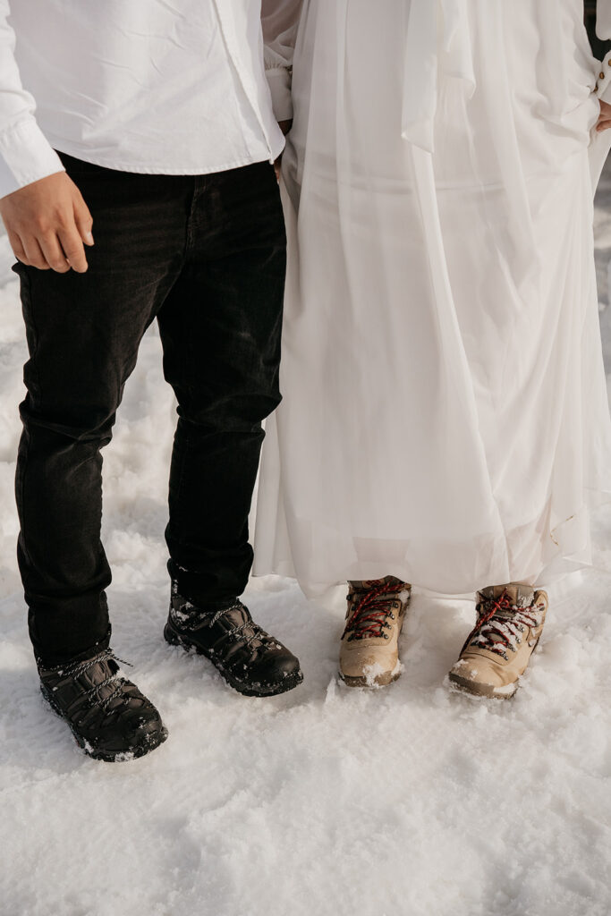 Couple wearing snow boots in winter scene.