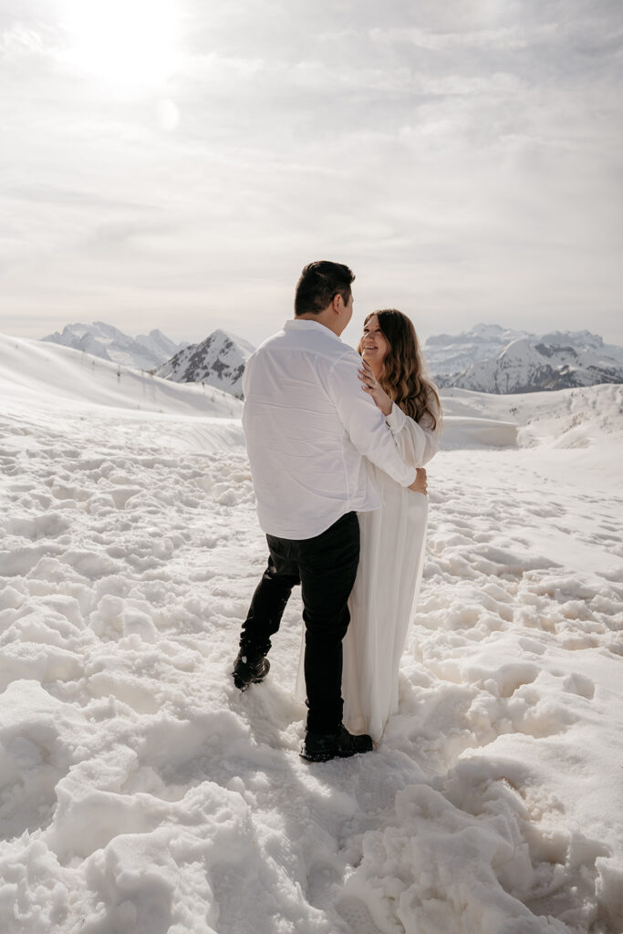 Couple embracing in snowy mountain landscape.