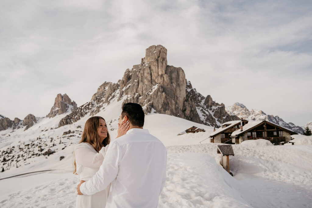 Couple embracing in snowy mountain landscape.