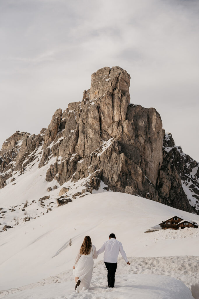 Couple walks towards snow-covered mountain peak.