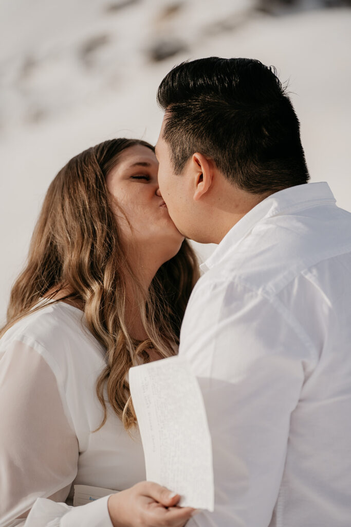 Couple kissing outdoors, holding paper notes.